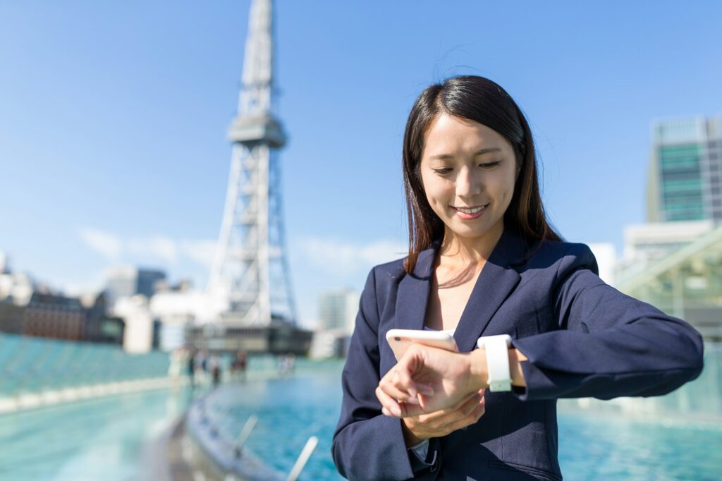 Businesswoman using mobile phone and smart watch