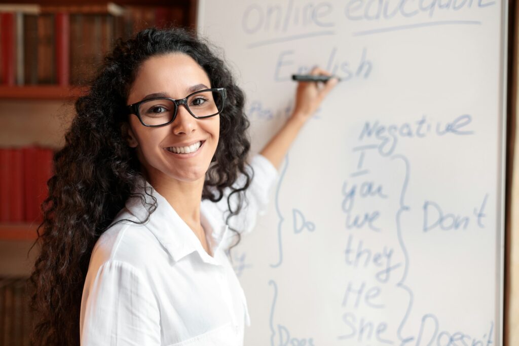 English teacher standing at board, explaining lesson to students