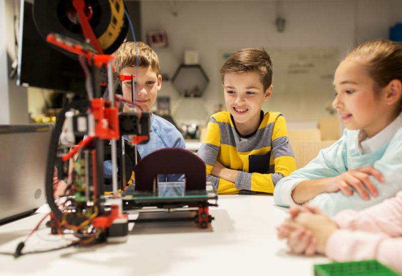 happy children with 3d printer at robotics school